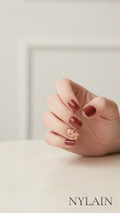Hand with red hearts nail wraps on a light background, featuring the brand NYLAIN.