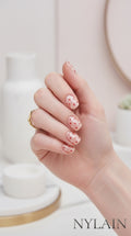 Hand with red and white polka dot nail wraps design holding a small object, with NYLAIN branding.